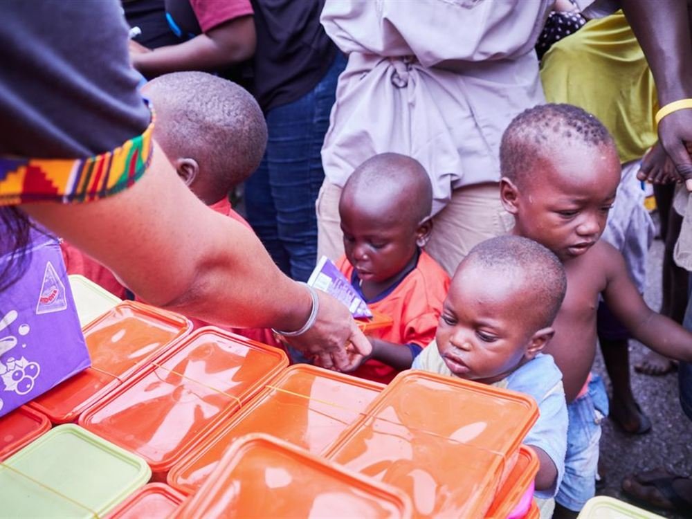 Children receiving meal boxes from a volunteer