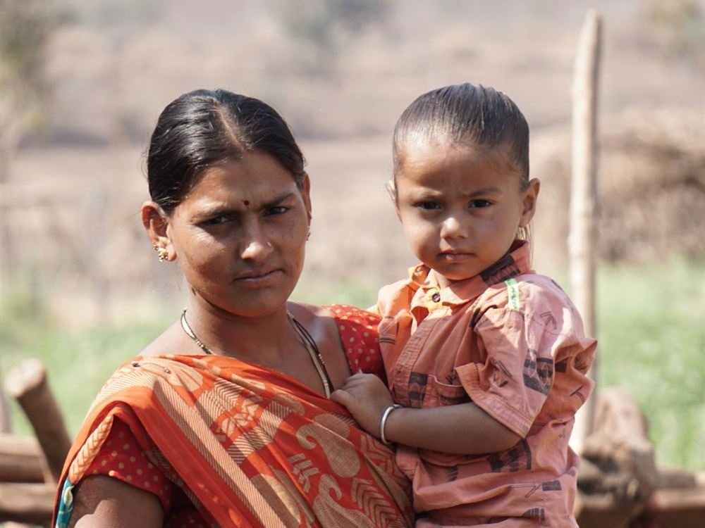 A mother holding her young child in a village
